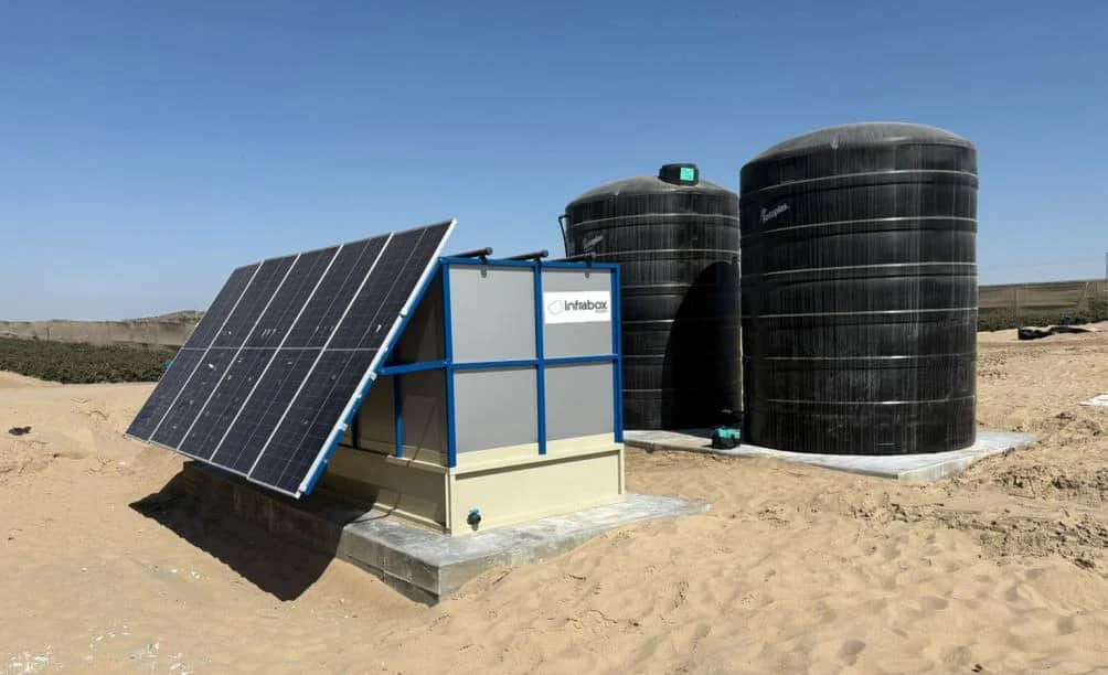 Une unité de traitement INFRABOX noire avec deux réservoirs d’eau noirs et leur tuyauterie, sur une dalle de béton
